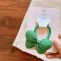 Close-up of a green fabric bow hair tie on display card with soft natural lighting - Hair Tie / Green