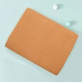 Folded double-layer cotton muslin swaddle blanket in orange brown on blue background - Turmeric