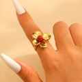 Detailed view of a gold four-petal flower ring with a red bead center on model hand - Gold (8959)