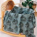 Blue muslin baby swaddle blanket featuring giraffe and elephant prints on a wooden crib - Grey Blue Animal Print