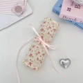 Detailed macro view of a floral fabric makeup brush roll wrap with a soft pink ribbon tie - Twill Floral Red