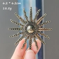 Baroque vintage sunburst brooch in retro gold finish held in hand showing 6.2cm size - Sun