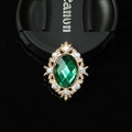 Macro detail of oval green gemstone brooch with gold frame and sparkling rhinestones - Gold Green