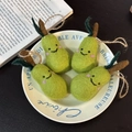 Handmade wool felt pear keychain with smiling face and green leaves in a rustic bowl - Generous Pear Collection