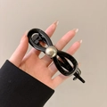 Barrette noeud noir brillant avec perle argentée tenue par une main féminine - Pince Torsadée en Perle Artificielle / Noir Brillant