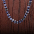 Détail macro de perles en pierre sodalite bleue à texture blanche sur fond en bois - Collier Pierre à Points Bleus