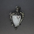 Detailed view of a heart-shaped white crystal pendant with gothic wing and skull metalwork - White Crystal