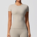 Détail d'un t-shirt de yoga ajusté montrant le col rond et le tissu mat élastique - Marron Camel
