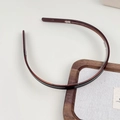 Detail view of tortoiseshell acetate headband with non-slip teeth on linen background - Brown