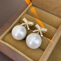Detalle de pendientes de lazo con circonitas y perlas sobre terciopelo marrón - Colgantes de perlas con lazo blanco