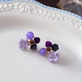 Close-up of purple flower stud earrings with cat eye stones and crystals on white ceramic - Purple