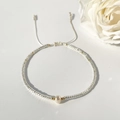 Dettaglio di bracciale con perle bianche e cordino regolabile su uno sfondo bianco - Stile Perla d'Acqua Dolce Bianca / Argento Trasparente/Bianco