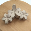 Beige floral claw clip with three matte frangipani flowers on a wooden stand - Matte Triple Plumeria Claw [Cream White]