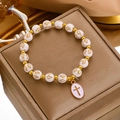 Detailed view of white beads with golden crosses and an oval pendant on a gift box - White Bead Gold Cross Bracelet (12005)