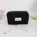 Detail of black bubble waffle fabric makeup bag with white label and zipper closure - Black