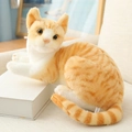Realistic orange tabby plush cat toy in a lying position on books for home decor - Lying Orange Cat