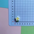 Top-down macro shot showing 1.5cm resin frangipani flower accessory on a ruler scale - White