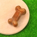 Reddish-brown carved agate stone bone figurine displayed on a wooden tray - Yellow Jasper
