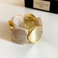 Detailed shot of retro gold-tone metal and beige marble resin link bracelet on white base - Gold-Beige