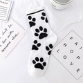 White cotton mid-calf sock featuring a black paw print pattern on a desk setting - Black White Paw (No. 08)