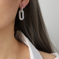 Orecchini a cerchio ovali in argento testurizzato con design a doppio anello su modella - Color Acciaio