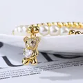 Detalle de una pulsera de perlas con un colgante de oso dorado y microcristales incrustados - Oso de Piedra Completa Sosteniendo Corazón