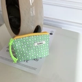 Detalle de la bolsa de cosméticos floral con cremallera amarilla y etiqueta de marca tejida - Cuadrícula Verde