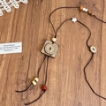 Detailopname van bohemian houten kralenketting met bloemhanger op houten ondergrond - Vierkante stijl (4# Ketting-Koffie-Vierkant)