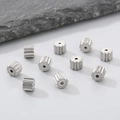 Makroaufnahme von 10 silbernen Edelstahl-Zahnradperlen für DIY-Schmuckherstellung - Zahnradform / Stahlfarbe