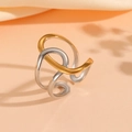 Close-up of wavy gold and silver interlaced stainless steel ring on pink satin fabric - Minimalist Abstract Line Style (#6)