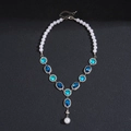 Dettaglio macro della collana vintage con gemme blu e perla su sfondo nero testurizzato - Collana Blu
