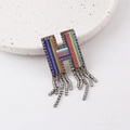 Macro detail of H-shaped brooch with colorful beadwork and dangling rhinestone tassels - Letter H