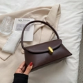 Retro deep brown underarm bag with golden oval clasp on a minimalist bed setting - Coffee