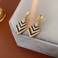 Makroaufnahme von goldenen geometrischen Ohrringen mit Strasssteinen auf Samt - Hoop-Stil (Gold)