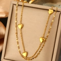 Dettaglio di una collana dorata a strati con pendenti a cuore su portagioie in seta - Doppia Catena Multi-Cuore