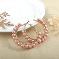 Detail of rose gold hoop earrings with handmade pink pearl beads on textured background - Rose Gold