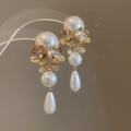 Primer plano detallado de pendientes de flores doradas con perlas y cristales - Oro-Blanco