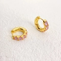 Elegant gold hoop earrings with pink zircon stones on white textured background - Pink