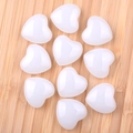 Polished white heart-shaped crystal gemstones on a natural wood surface for decor - Smelted White Jade