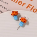 Macro shot of glass mushroom charms with orange caps, red dots, and blue stems - No.18 (Orange Cap Red Dot Light Blue Stem)