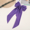 Detail view of a large purple satin bow hair clip with flowing elegant ribbons - Purple