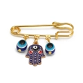 Golden pin brooch featuring a blue Hamsa hand and evil eye charms on a white background - Pin with Red Eye Blue Hamsa and Blue Eye Beads
