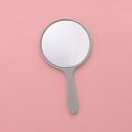 Mini round grey handheld makeup mirror with plastic handle on a pink surface - 5.5x10cm / Light Green