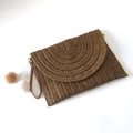 Detailansicht einer dunkelbraunen gewebten Stroh-Clutch mit dekorativen Pompons - Dunkelbraun