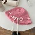 Pink knit bucket hat with white ribbon bow tie detail shown in a stylish layout - Hat / Pink