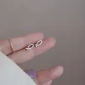 Minimalist 925 sterling silver hollow fish stud earrings displayed on a finger for scale - Hollow Fish / Silver