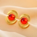 Vista macro di orecchini placcati in oro con pietra rossa su velluto beige - Orecchini Tondi a Raggi di Sole con Pietra Rossa (5款)