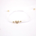 Detail of white braided bracelet featuring a gold heart charm with pavé cubic zirconia - White