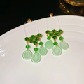 Macro view of green rhinestone cluster earrings with translucent leaf drop pendants - Green