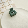 Close-up of a matte dark green square hair claw clip on a minimalist beige tray - Dark Green